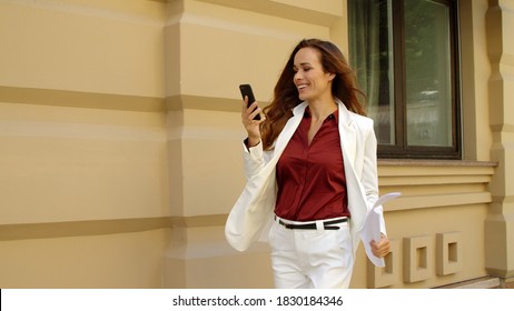 Joyful Business Woman Call Video Online On Mobile Phone Outdoors. Executive Woman Walking At City Street. Smiling Professional Having Video Chat Outside. Happy Woman Having Vide Call On Smartphone