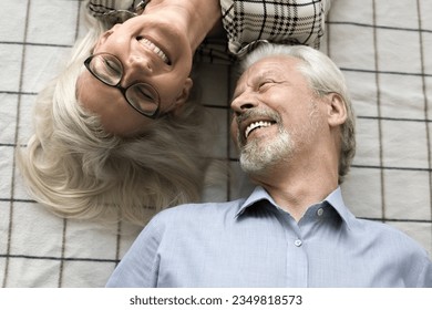 Joyful carefree older couple relaxing on bed top view. Cheerful retired husband and wife lying on backs, having fun, talking, laughing, enjoying retirement, close relationship, leisure - Powered by Shutterstock