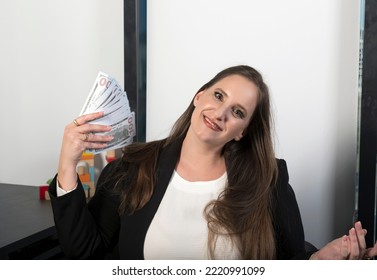 Joyful Caucasian Office Worker Manager Holding Bundle Dollars In Hands Counting Cash Paper Money. Portrait Of An Happy Young Girl With Long Brunette Hair Holding Fan Of Cash Money In Dollar Banknotes