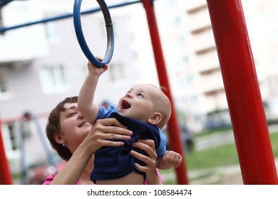 Joyful Child Is Hanging On Rings At Playground