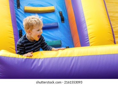 Joyful child jumping on colorful inflatable trampoline. Little boy 3-4 years playing on outdoors playground in sunny summer day. Kids fun activity concept. Children's leisure.