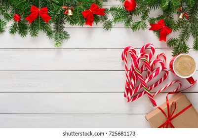 Joyful christmas background. Beautiful present boxes, traditional candy cane lollipops, hot coffee cup and fir tree branches border on wood. Preparing for winter holidays concept, top view, copy space
