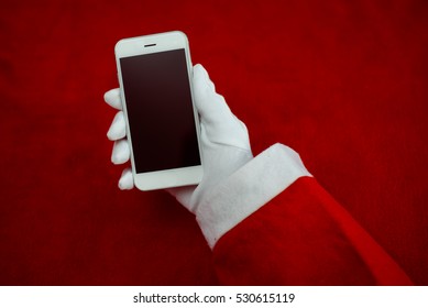 Joyful Christmas online shopping. Closeup on Santa Claus working using mobile tablet computer on table background. Social network, electronic commerce, banking, logistic operations, resolution