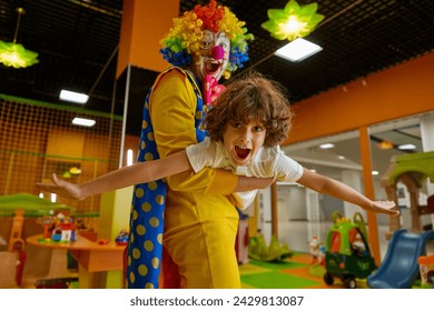 Joyful clown and kid feeling excitement playing game together at daycare center - Powered by Shutterstock