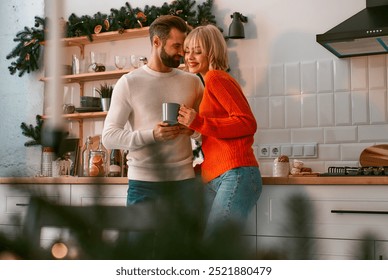 A joyful couple deeply in love shares a warm and intimate moment in a beautifully decorated kitchen during the enchanting holiday season, embodying the true essence of winter coziness and happiness - Powered by Shutterstock