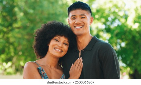 A joyful couple embraces each other outdoors under a clear blue sky. Smiling To Camera  - Powered by Shutterstock