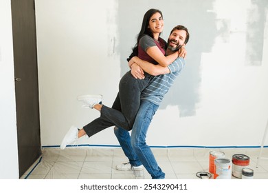 Joyful couple embraces while painting and decorating their new apartment, radiating love and happiness in their cozy home - Powered by Shutterstock