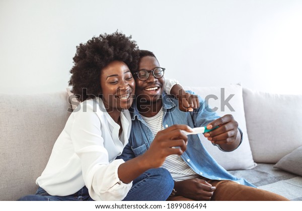 Joyful couple finding out results of a pregnancy\
test at home. Happy couple looking at pregnancy test. Woman\
surprising her husband with positive pregnancy test, he seems\
reasonably pleased