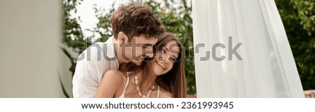 joyful couple, happy man hugging cheerful woman while standing together near white tulle, banner