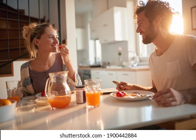 Joyful couple having breakfast together in the kitchen