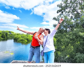 A joyful couple kisses while expressing their happiness by a serene lake surrounded by lush greenery. - Powered by Shutterstock