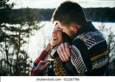 Casal bonito e alegre abraços. Jovem em um suéter abraça uma menina de trás de fundo no inverno. O conceito de uma relação de sucesso e momentos felizes