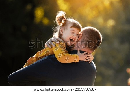 Joyful dad hugs his little smiling daughter. Single daddy and child have fun, laugh and enjoy nature outdoors at autumn park. Concept of parental care and happy carefree childhood. Happy fathers day.