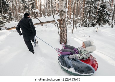 Joyful Dad Rides His Daughter On A Sleigh In The Snowy Forest. High Quality Photo