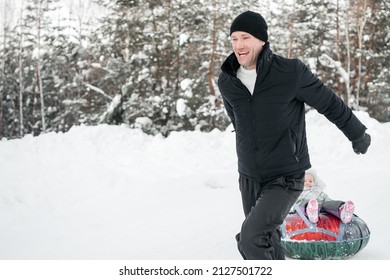 Joyful Dad Rides His Daughter On A Sleigh In The Snowy Forest. High Quality Photo