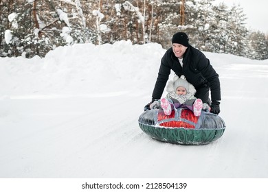 Joyful Dad Rides His Daughter On A Sleigh In The Snowy Forest. High Quality Photo