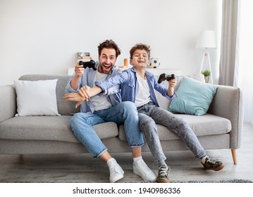 Joyful dad and son with joysticks playing video games at home, boy distracting father with hand - Powered by Shutterstock