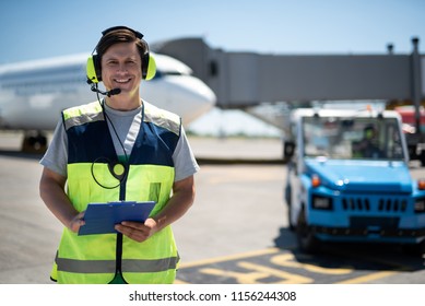 Joyful Day At Airport. Waist Up Portrait Of Smiling Airport Worker. Car, Plane, Sky And Runway On Blurred Background