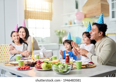 Joyful Day. Happy Latin American Family With Children Looking Suprised About Firework Sparkler On A Cake While Celebrating Birthday Together At Home