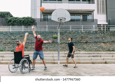joyful disabled man in wheelchair playing basketball with two friends with a ball, concept of adaptive sports and physical activity, rehabilitation for people with physical disabilities - Shutterstock ID 1477967360