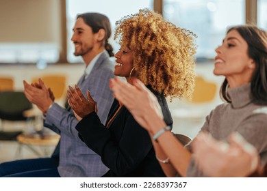 A joyful diverse audience is clapping hands in a conference room after a successful presentation. - Shutterstock ID 2268397367