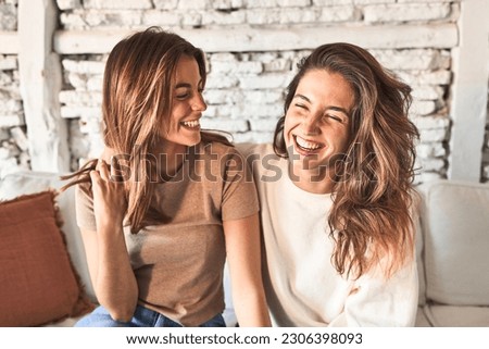 Joyful duo, sharing laughter on the cozy sofa.