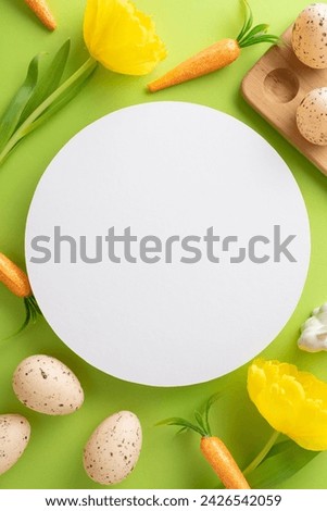 Joyful Easter scene. Vertical top view of eggs in a holder, carrots for the bunny, and yellow tulips on green with circular area for text