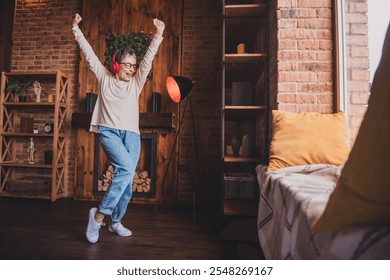 Joyful elderly woman dancing in casual style pullover indoors, enjoying leisure time on a bright weekend day in her apartment - Powered by Shutterstock