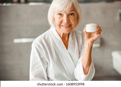Joyful elderly woman demonstrating cosmetic product and smiling stock photo