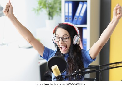 Joyful Enthusiastic Presenter In Headphones With Microphone Looks At Computer Monitor. Sports Commentator