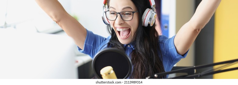 Joyful Enthusiastic Presenter In Headphones With Microphone Looks At Computer Monitor. Sports Commentator Concept