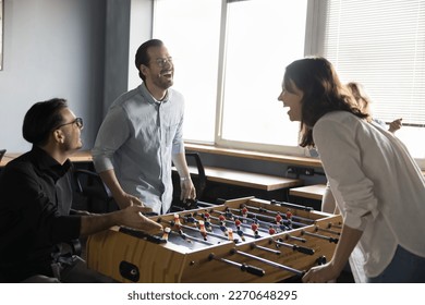 Joyful excited millennial couple of colleagues competing in table soccer on work break, laughing out loud at board game. Office friends playing tabletop football, having fun - Shutterstock ID 2270648295
