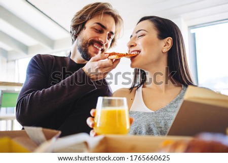 Joyful family couple have pizza break while working at home together