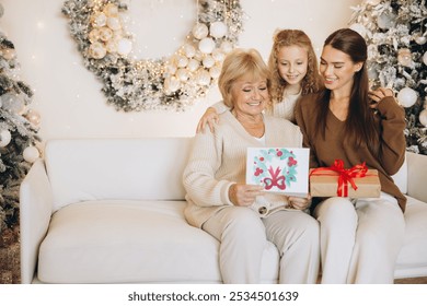 A joyful family gathering with grandmother, mother, and daughter exchanging gifts in a festive Christmas setting filled with holiday decorations and warm smiles. - Powered by Shutterstock