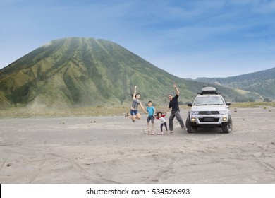 Joyful Family Jump On Volcanic Desert, Shot Outdoors