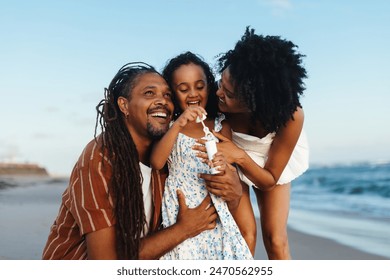 Joyful family moment at the beach featuring mother, father, and daughter having fun blowing bubbles together. - Powered by Shutterstock