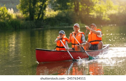 Joyful family of three canoeing on a calm river, with splashing water and lush greenery illuminated by sunlight at summer in bavaria, germany. Family on kayak ride. Wild nature and water fun on summer