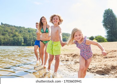 Joyful Family With Two Children Is Having Fun While Bathing In The Lake In Summer Vacations