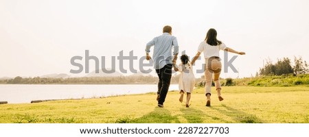 Joyful father and daughter running and laughing in a green meadow, with the sun setting in the background, on a weekend family outing, Back family fun together