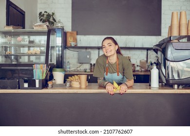 Joyful female barista standing behind counter in cafe - Powered by Shutterstock