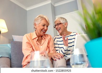 Joyful female friends having a conversation. Senior Women Socializing in Lounge Using Laptop Computer at Senior Care Center. Social Seniors. Portrait of two beautiful senior women
