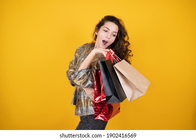 Joyful female shopaholic holding purchase bags yellow background, style fashion. Concept of shopping and sales of happy young girl with packages. High quality photo