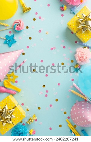Joyful festivity creativity. Vertical top view of table set with sweets, wrapped gifts, party hats, noise-maker, candles, straws, balloons, confetti on soft blue backdrop with available space for text