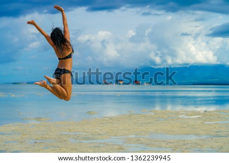 Joyful filipina jumping along the beach at Manjuyod Sandbar, Philippines