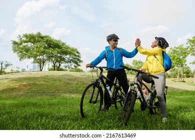 Joyful friends giving each other high five after finishing coming to destination point on bicycles
