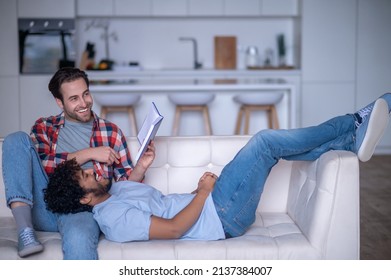 Joyful Gay Couple Reading A Book Together