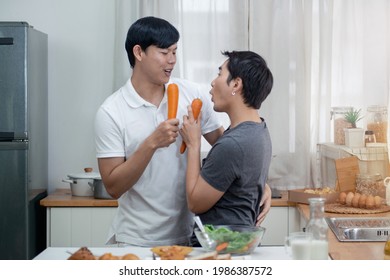 Joyful Gay Couple Singing And Dancing During Breakfast In Kitchen, Use Carrot Instead Of Microphone