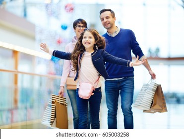 Joyful girl and her parents enjoying weekend in the mall