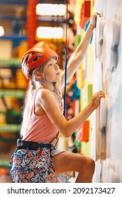 Joyful Girl At Indoor Climbing Wall. Kid In Helmet Having Fun At Bouldering Wall. Child Learning At Climbing Class. Family Sport, Healthy Lifestyle, Happy Family. 