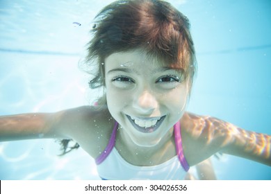 Joyful Girl Swimming Underwater In Pool